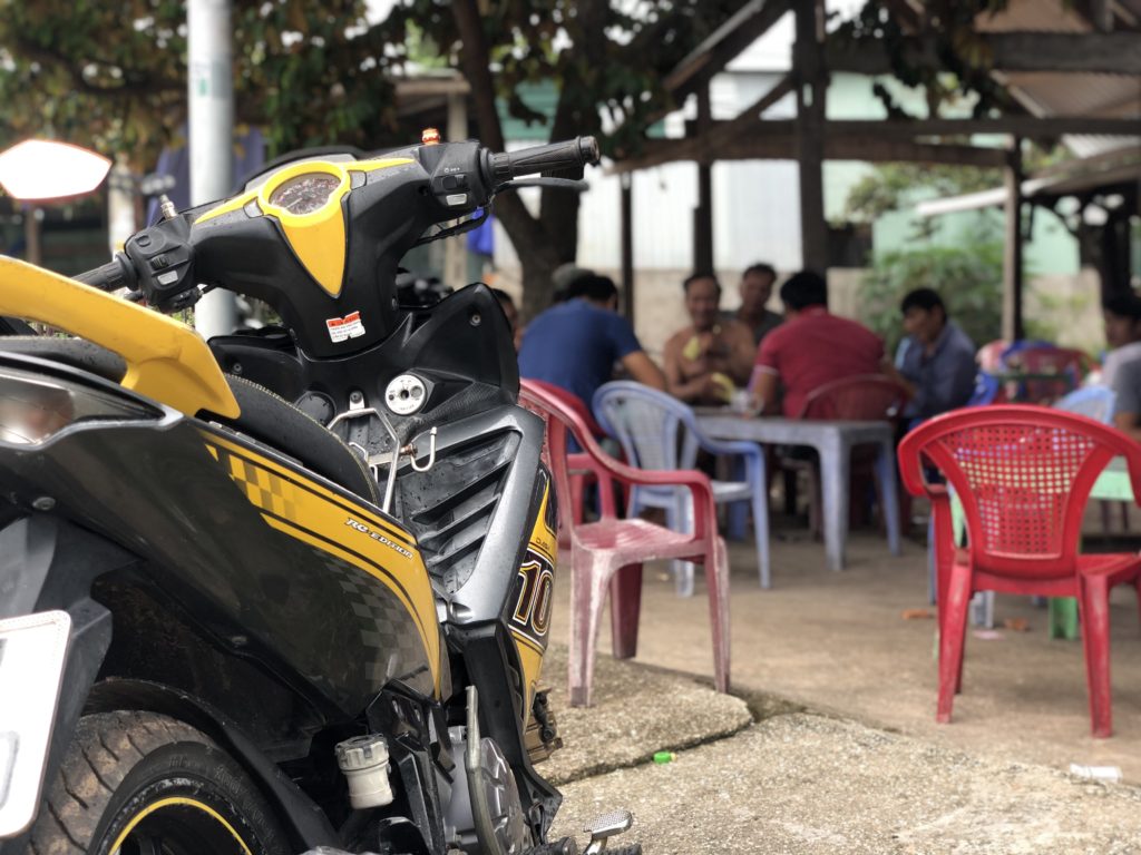 Yellow and black scooters, Vietnamese people enjoying a game in the background