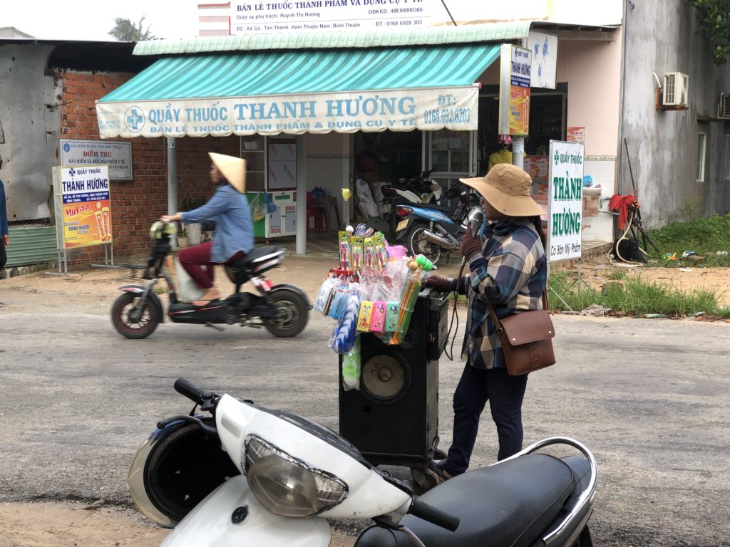路上でカラオケを歌い雑貨を販売するベトナム女性