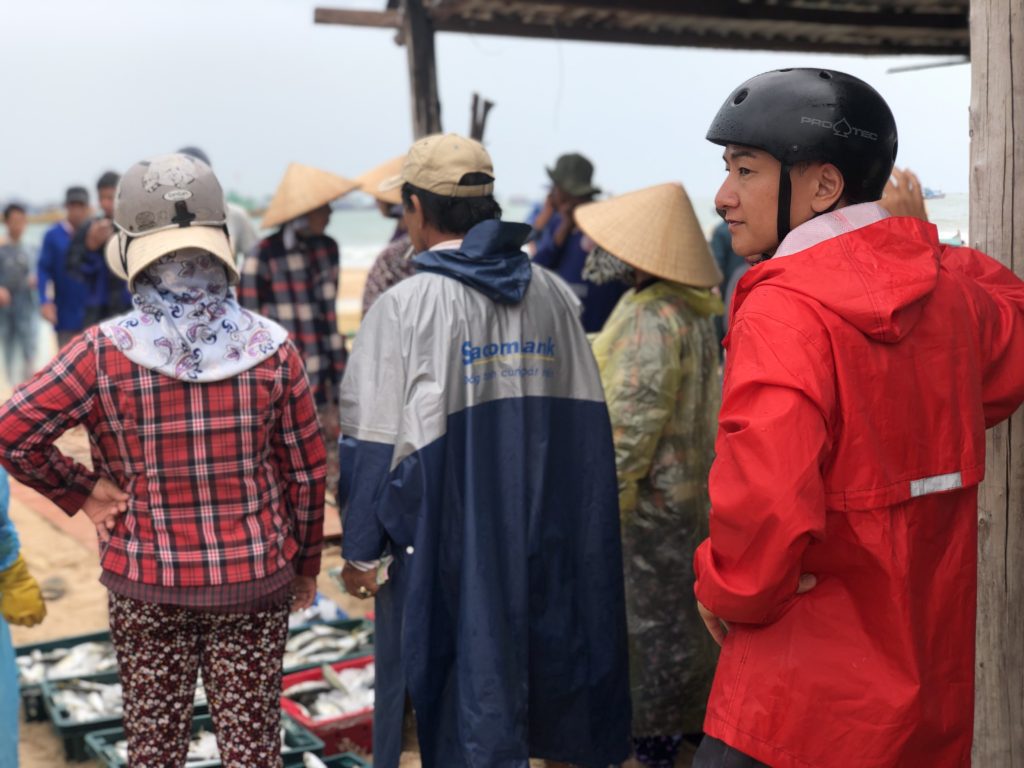 雨合羽を来た日本人とケガー村漁師と魚屋買付け人