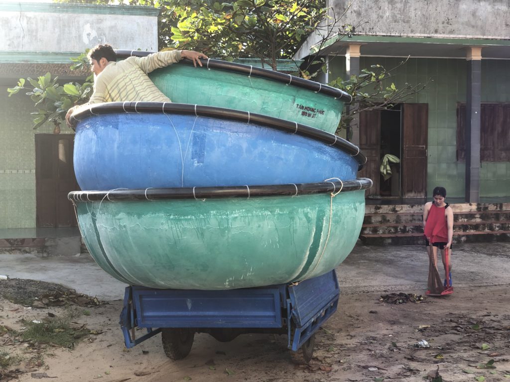 Vietnamese packing up to carry three Vietnamese-style boats on three-wheelers
