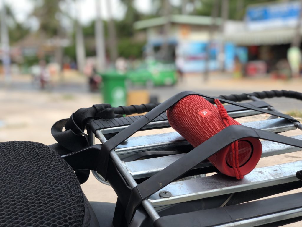 Wireless speaker secured to the back of a scooter with a rubber band