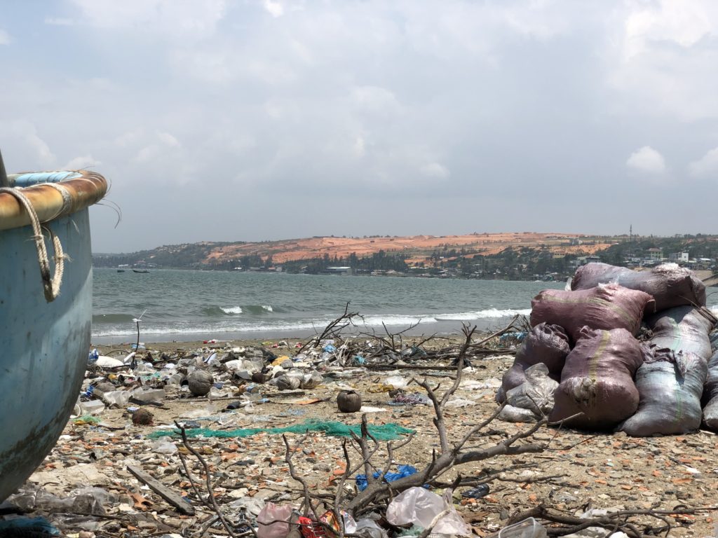 Mui Ne beach with trash and boats within view