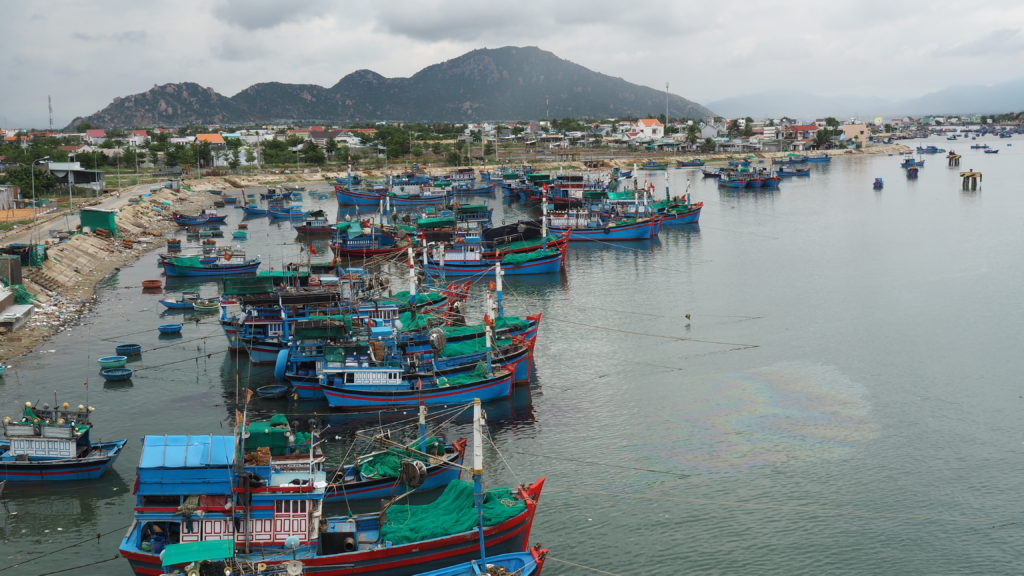 Boats docked on the river, oil spilling out