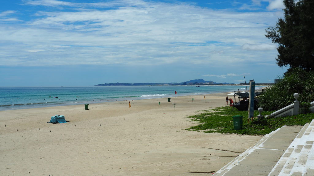 Blue sea Bai Dai Nha Trang Beach and some surfers
