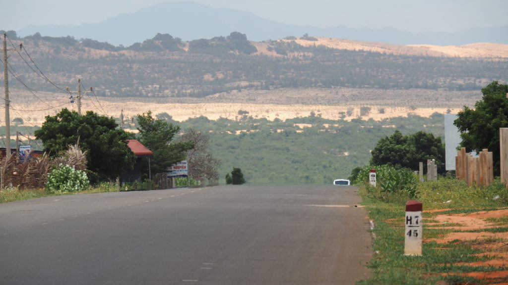 Sand dunes in the distance against the backdrop of hot asphalt roads
